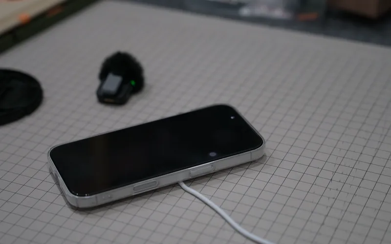 An iPhone lying flat on a cutting mat, charging on MagSafe
