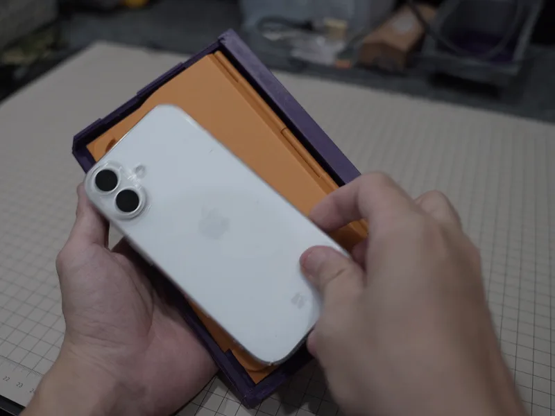 An iPhone resting on the orange prototype, which is much larger than the phone