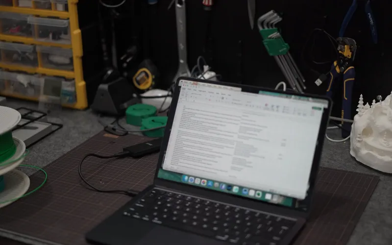 Laptop mở trên bàn làm việc, ổ cứng đặt bên cạnh