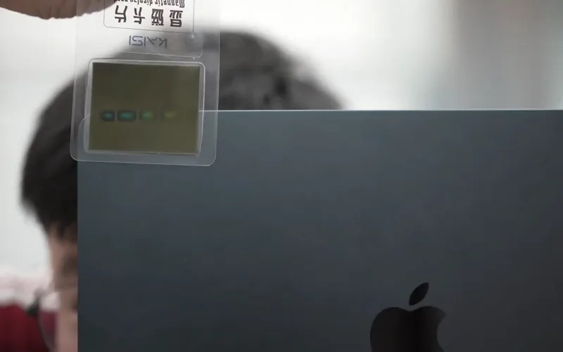 Một tấm thẻ dò nam châm áp lên lưng MacBook, hiện vị trí nam châm