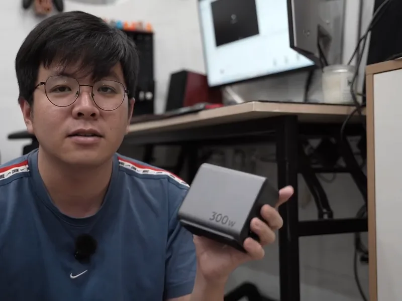 A hand holding a grey Ugreen charger the size of a palm