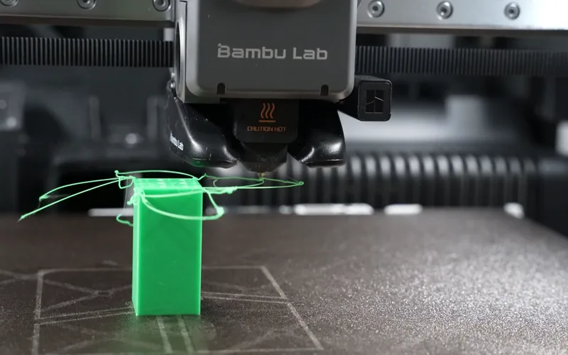 A green printed block whose overhang has collapsed into tangled strands