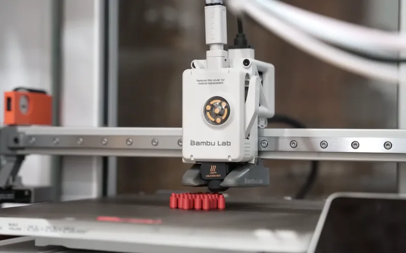 A Bambu Lab printer printing the red pins