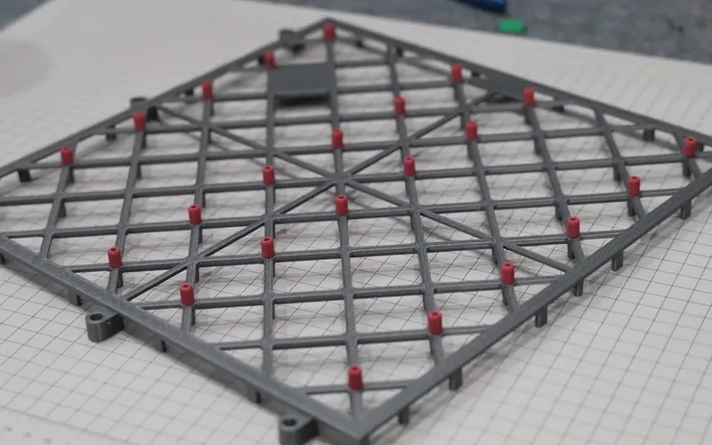 The grey tile with all its red pins, on a cutting mat